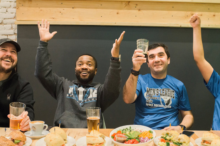 Group of people eating sandwiches and salads while drinking