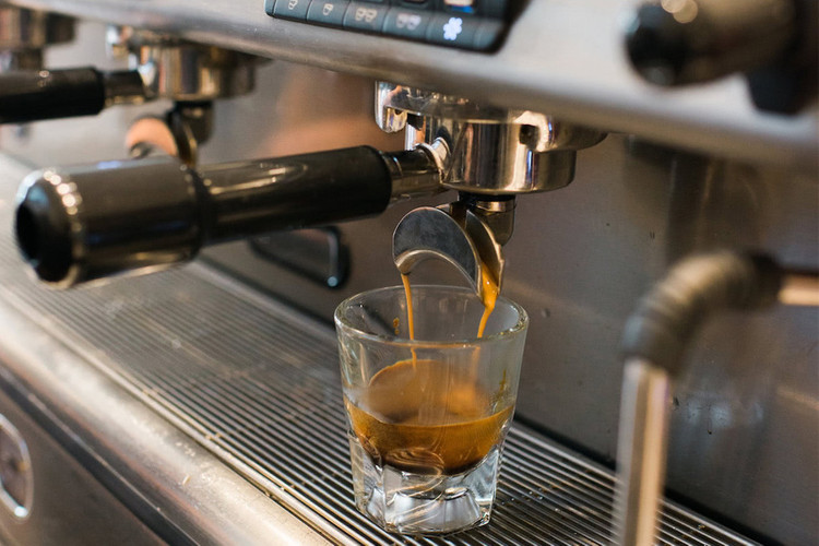 Espresso being poured from a machine to make a Cortado