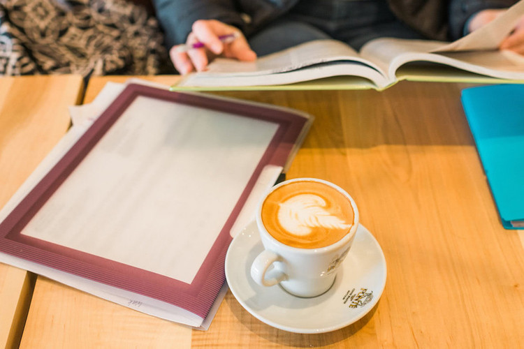 Women reading a book while drinking espresso drink